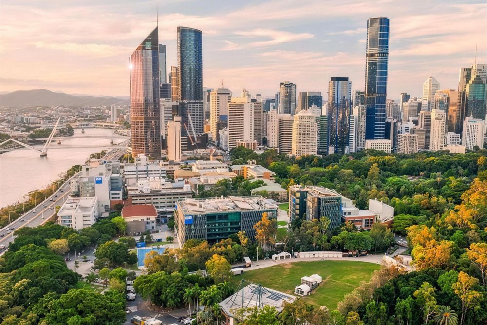 Brisbane CBD towers above the river and parklands at sunset