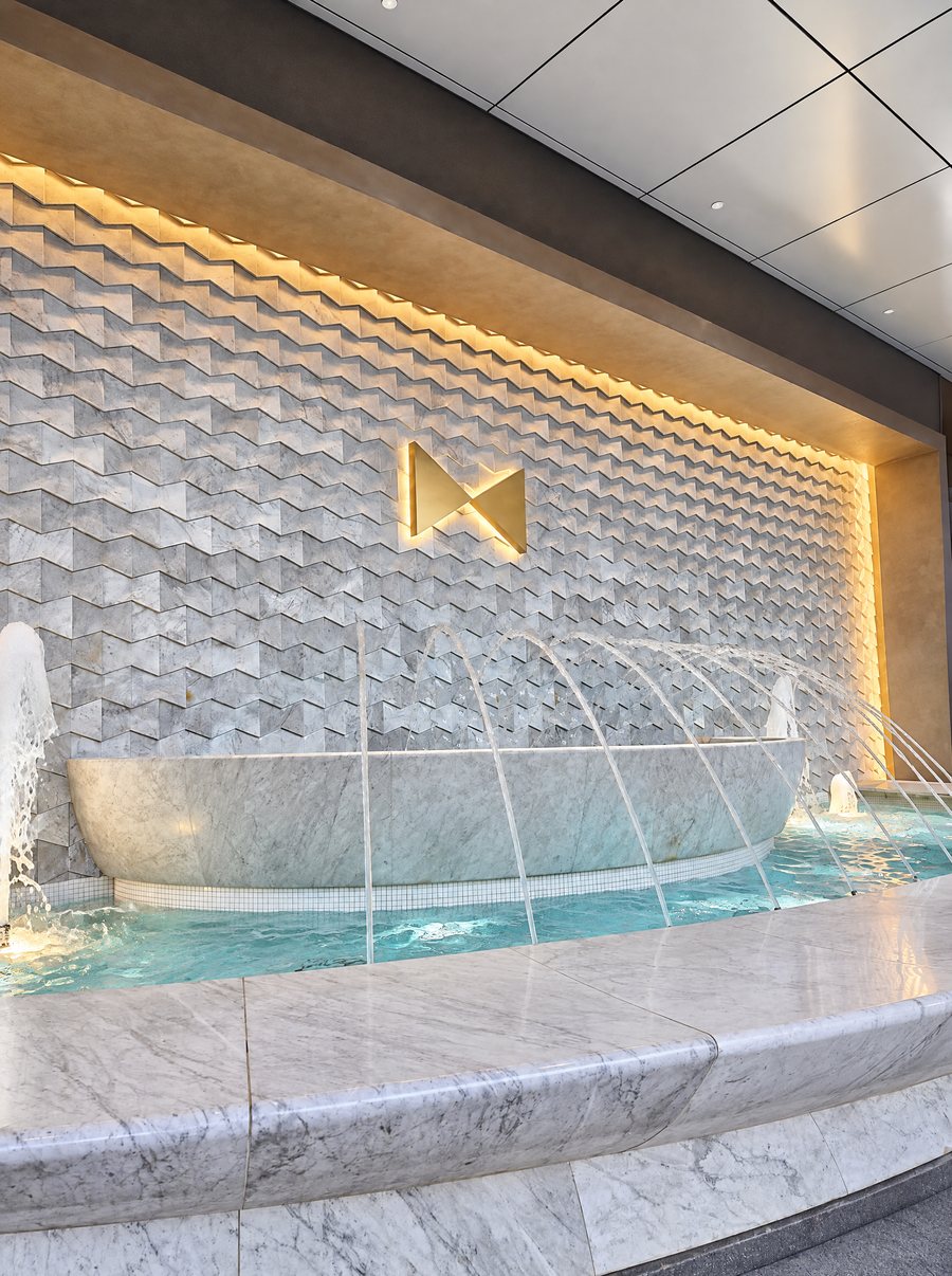 Fontainebleau Las Vegas, a marble fountain against a carved stone wall with the bow tie logo