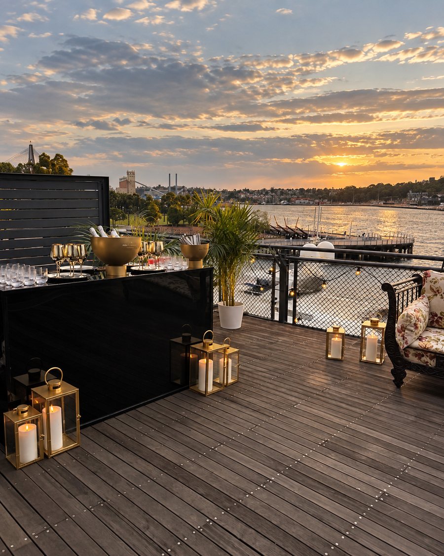 Pier One Sydney Harbour, Autograph Collection, deck bar set with gold ice buckets and lanterns at sunset over the harbour