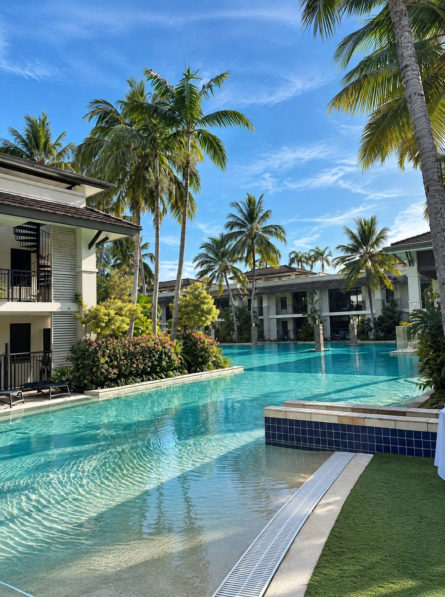 Pullman Port Douglas Sea Temple Resort & Spa, lagoon pool with a shallow beach entry, palms and two storey apartment wings along the water